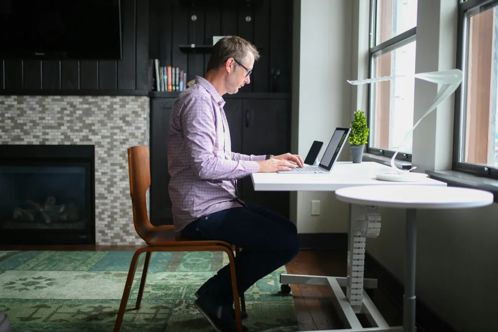 Man sitting at a home desk using a laptop and a tablet
