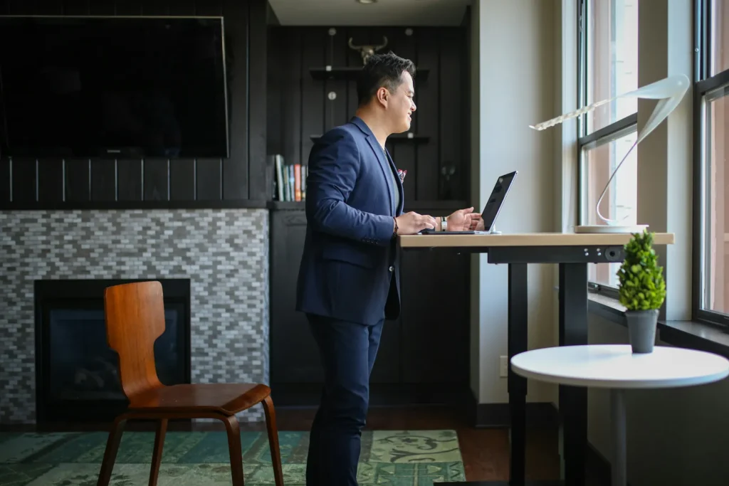 Man in a suit working on a laptop at a standing desk