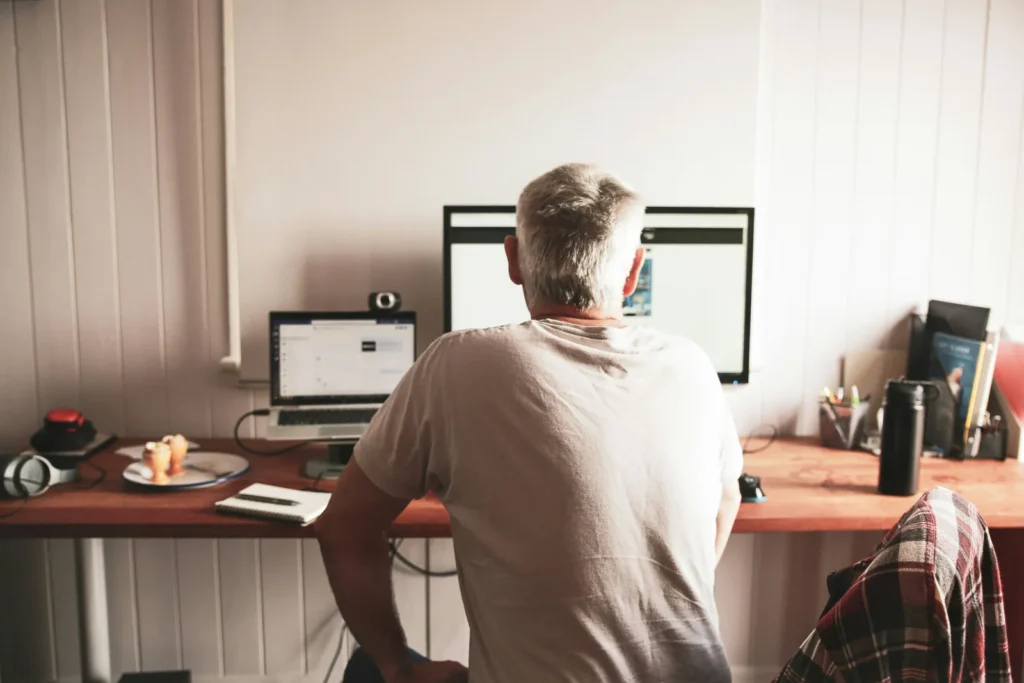 Older man seated at a desk in front of a computer screen