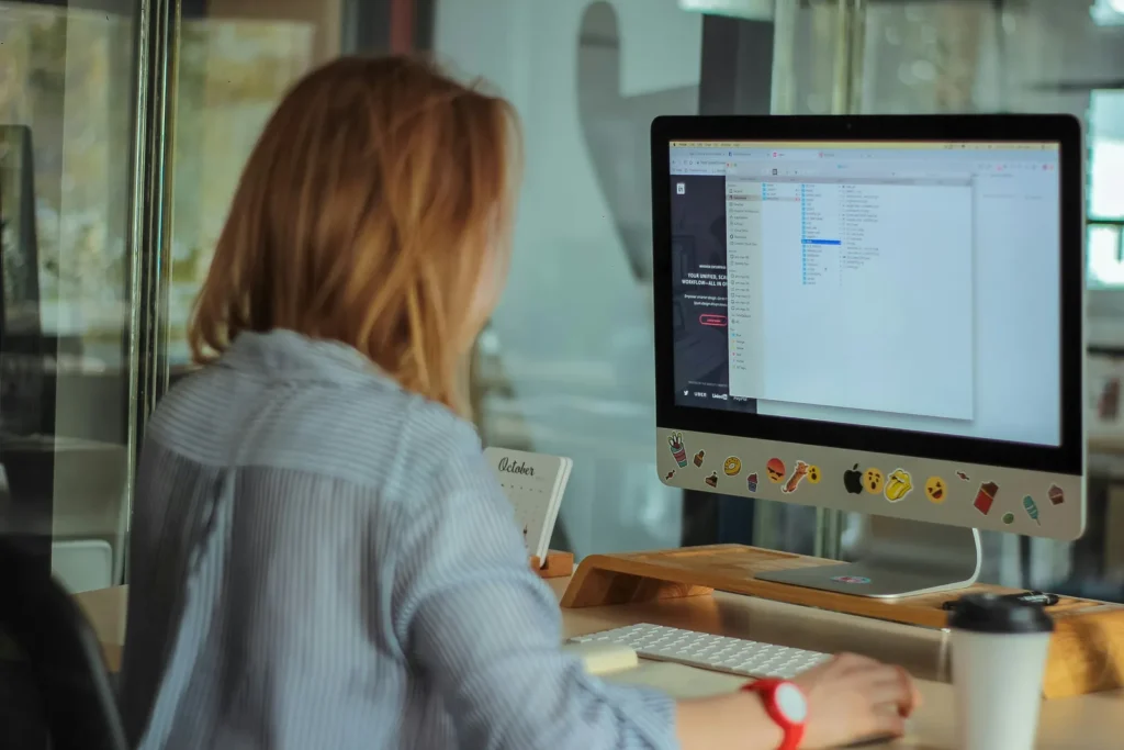 Woman at a desk with a computer monitor and a coffee cup