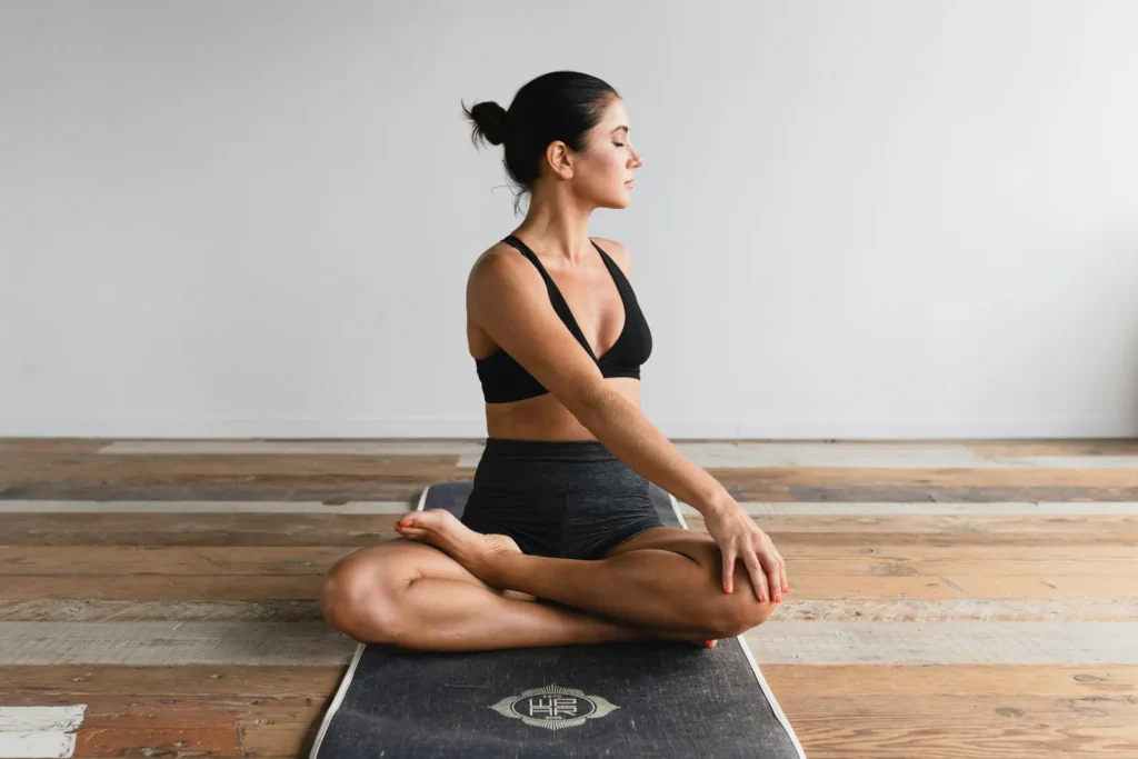 Woman sitting cross-legged on a mat in a bright room