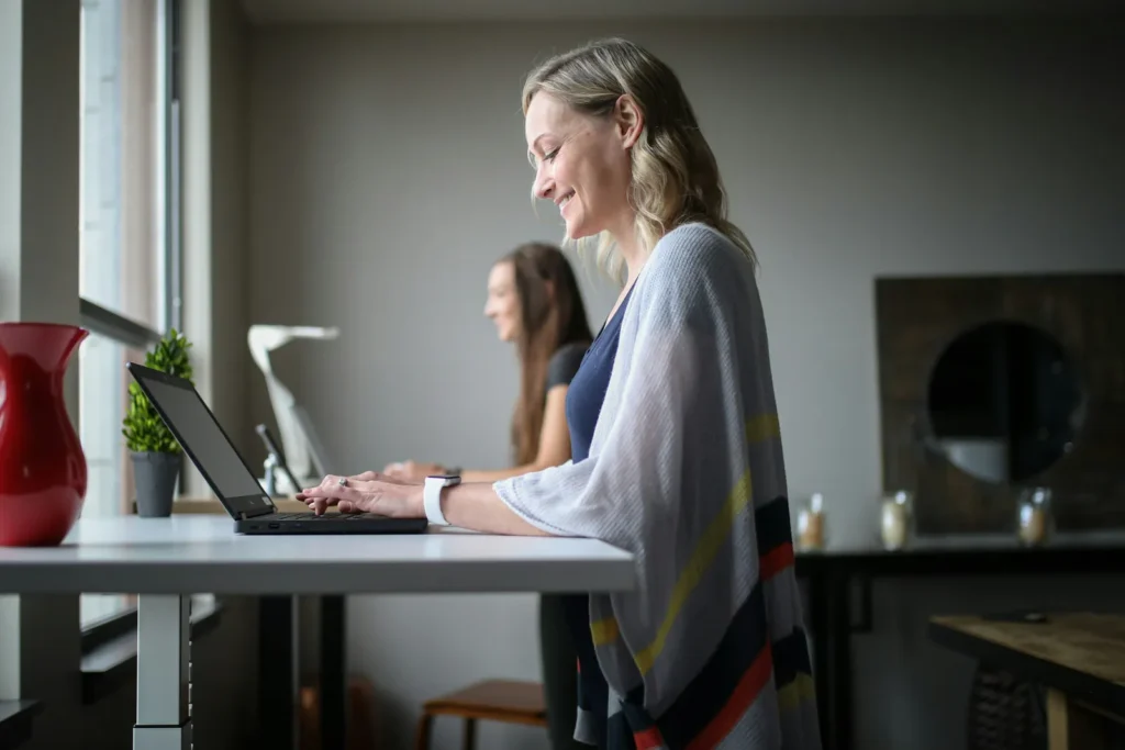 Smiling woman typing on a laptop at a desk