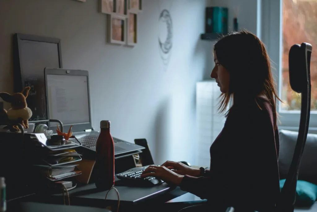 Woman typing at a computer in a dimly lit office
